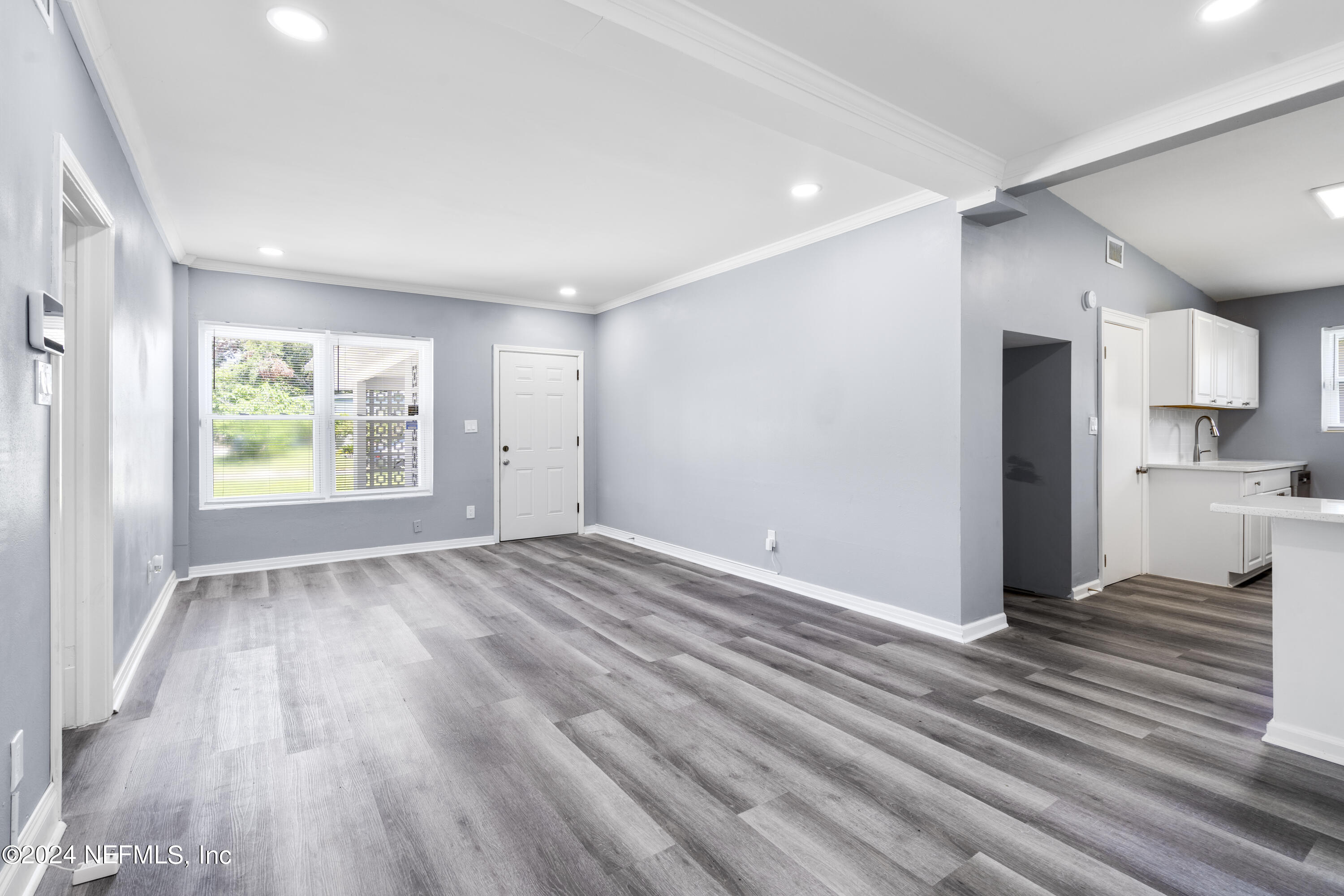 a view of an empty room with wooden floor and a window