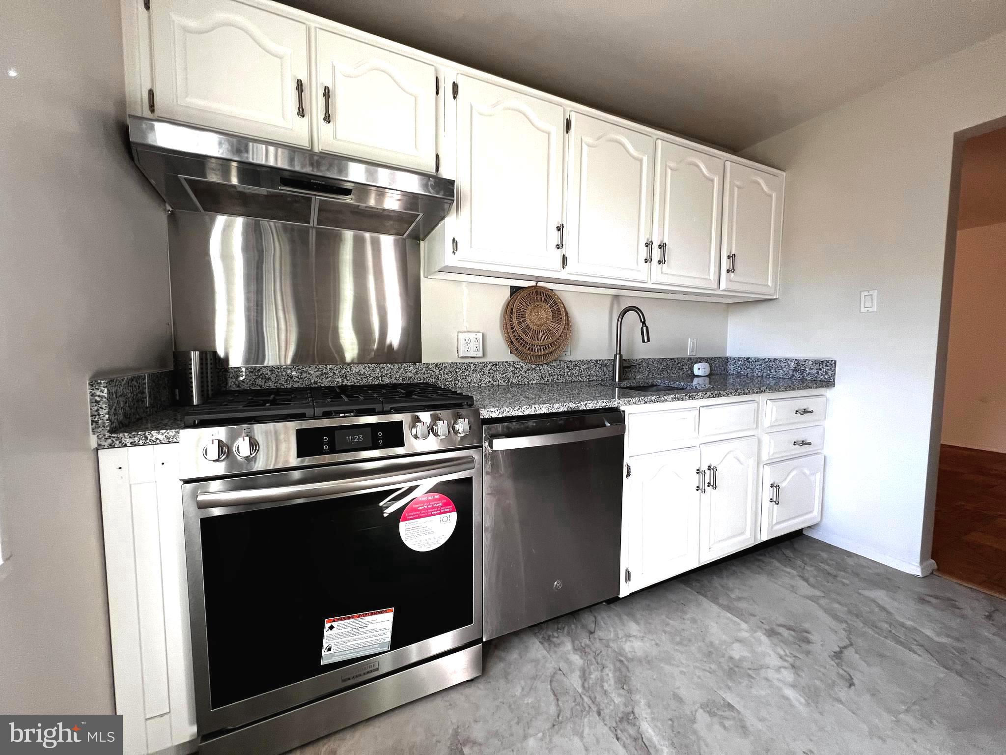 a kitchen with granite countertop white cabinets and black appliances