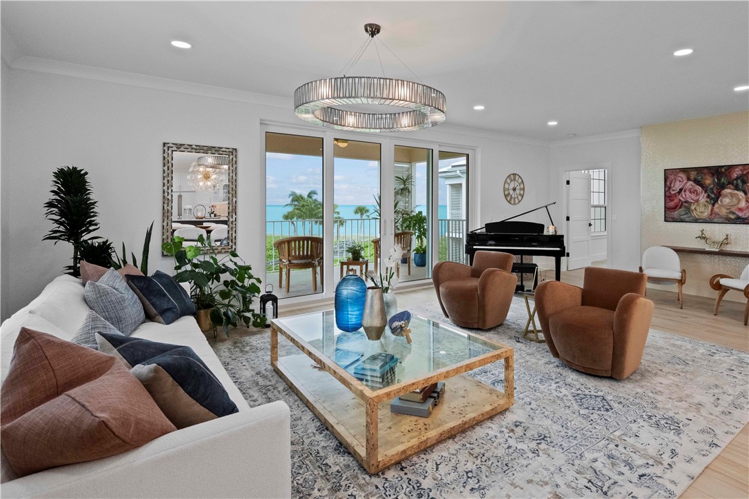 a living room with furniture a chandelier and a floor to ceiling window