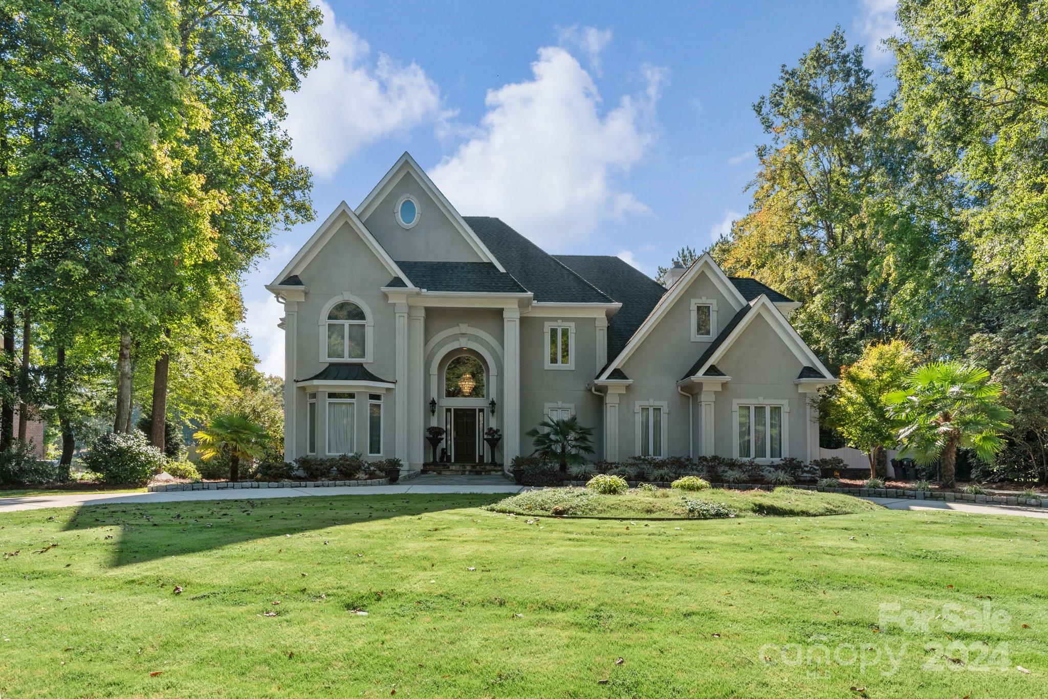 a front view of a house with a garden and trees