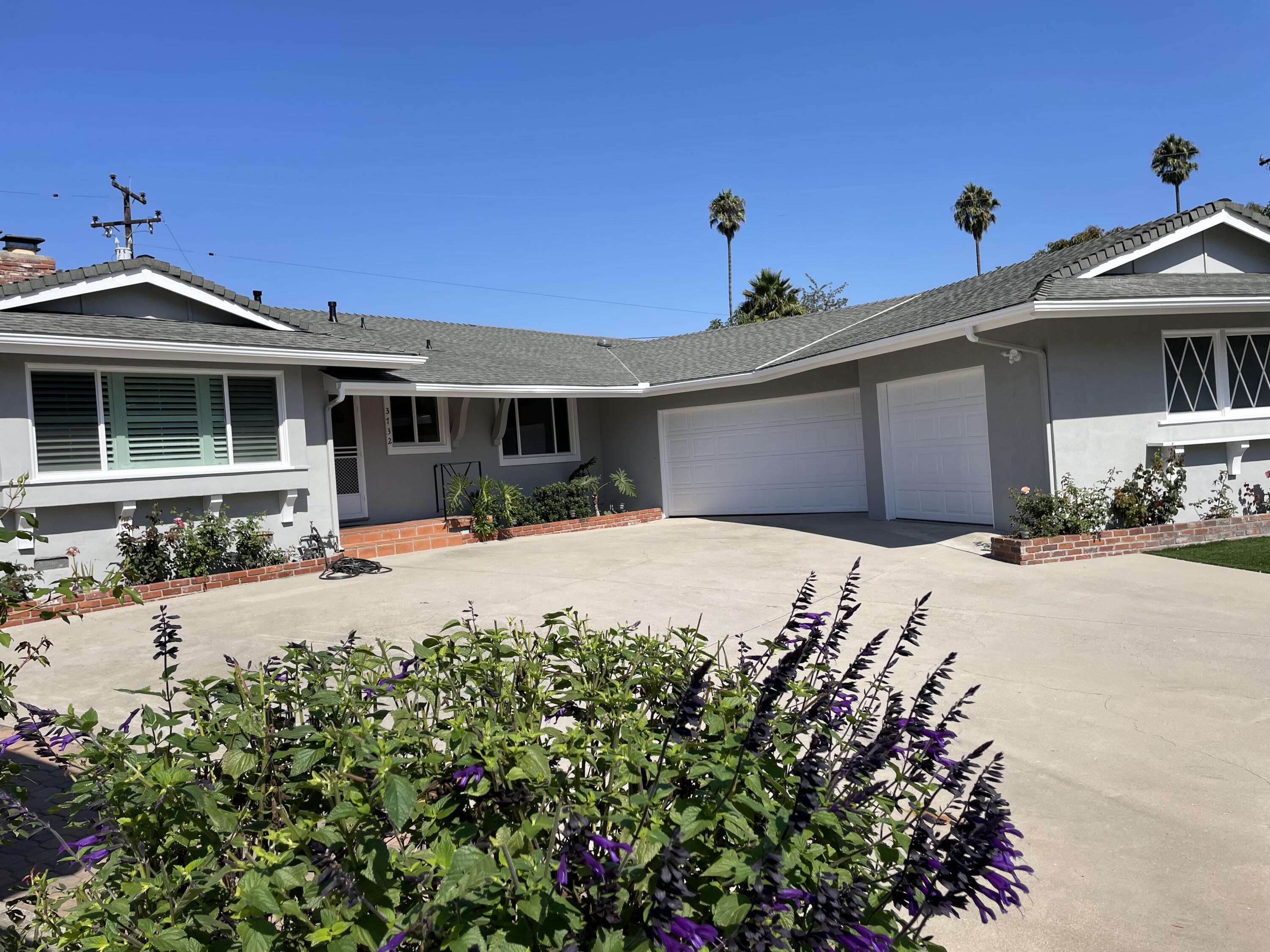 a front view of a house with a yard and potted plants