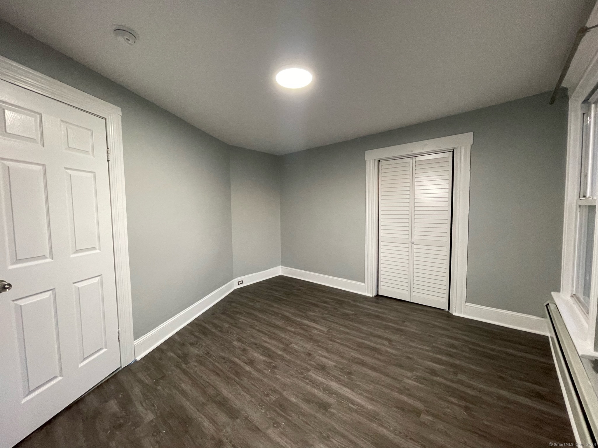 an empty room with wooden floor and closet