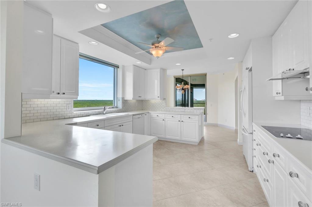 Kitchen featuring a raised ceiling, kitchen peninsula, and white cabinets