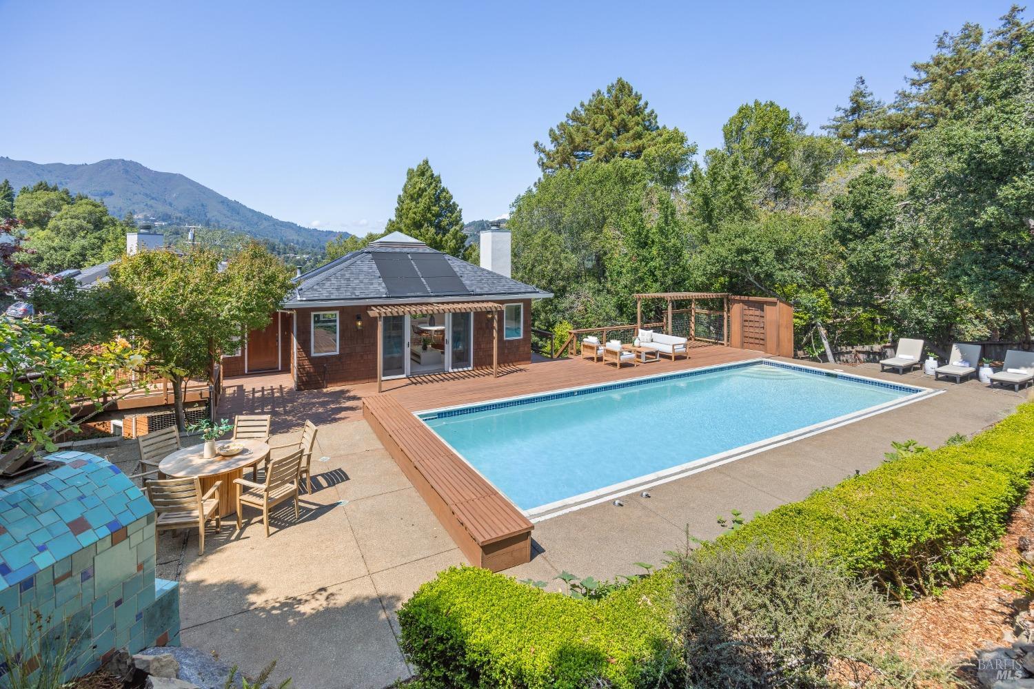 a view of swimming pool with outdoor seating and trees in the background