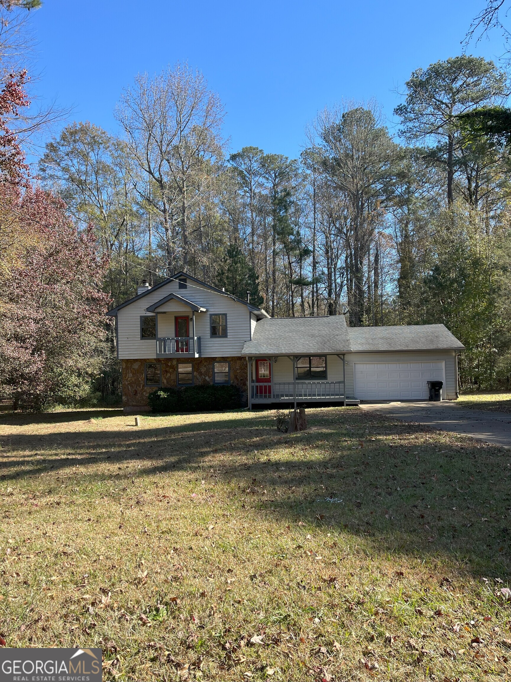 a front view of house with yard and trees in the background