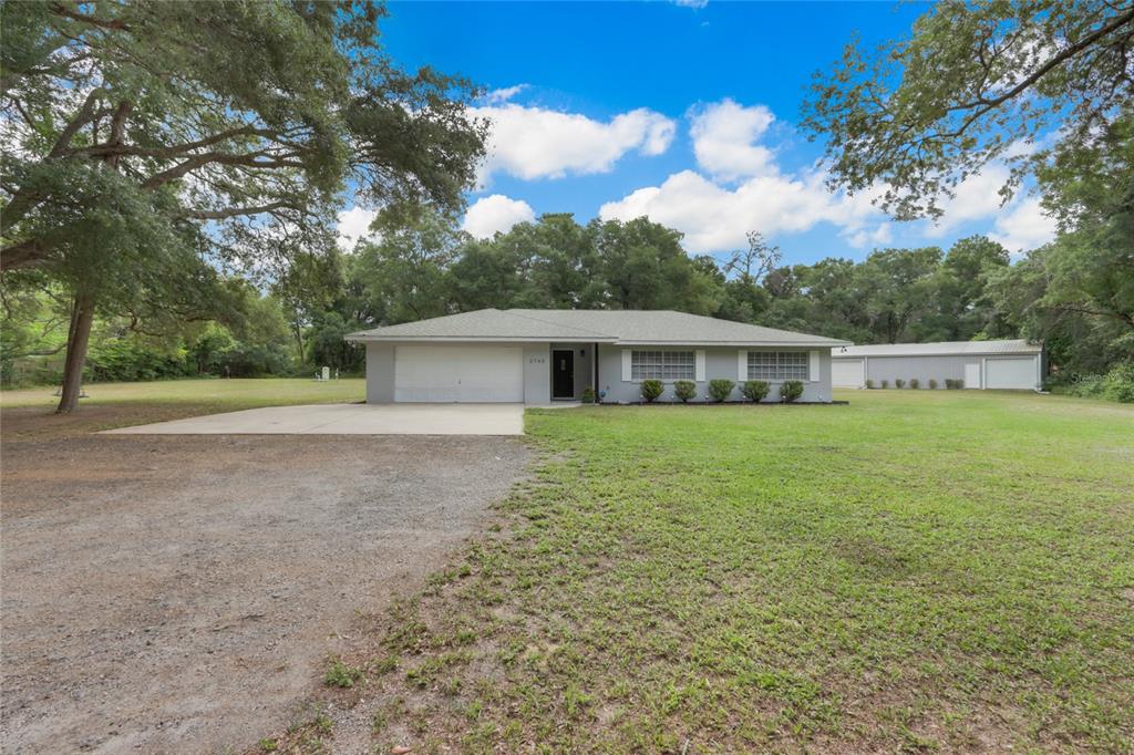 a front view of house with yard and trees in the background