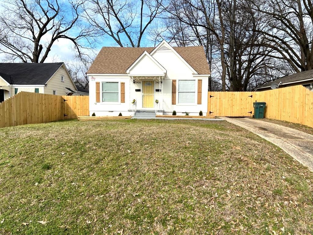 a front view of a house with a garden and tree