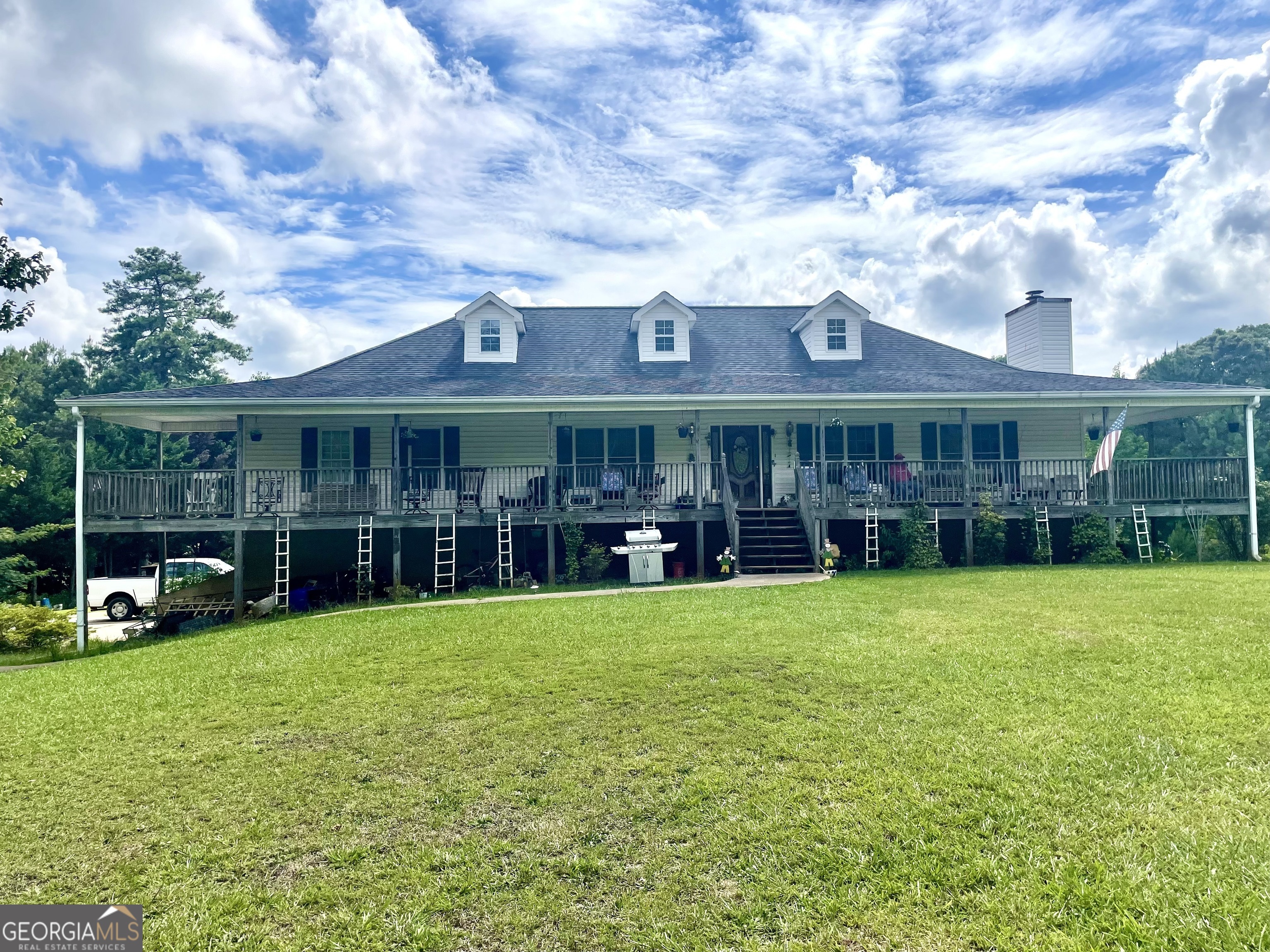 a view of a house with a big yard and large trees