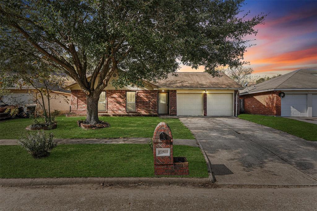 Charming single-story brick home with a two-car garage. Beautiful mature tree. The driveway and walkway lead to a welcoming entrance.