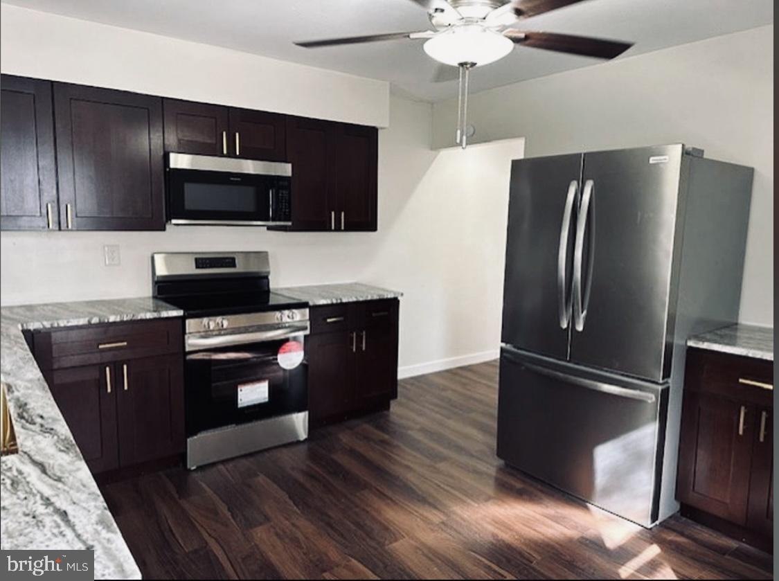 a kitchen with stainless steel appliances wooden cabinets and wooden floor