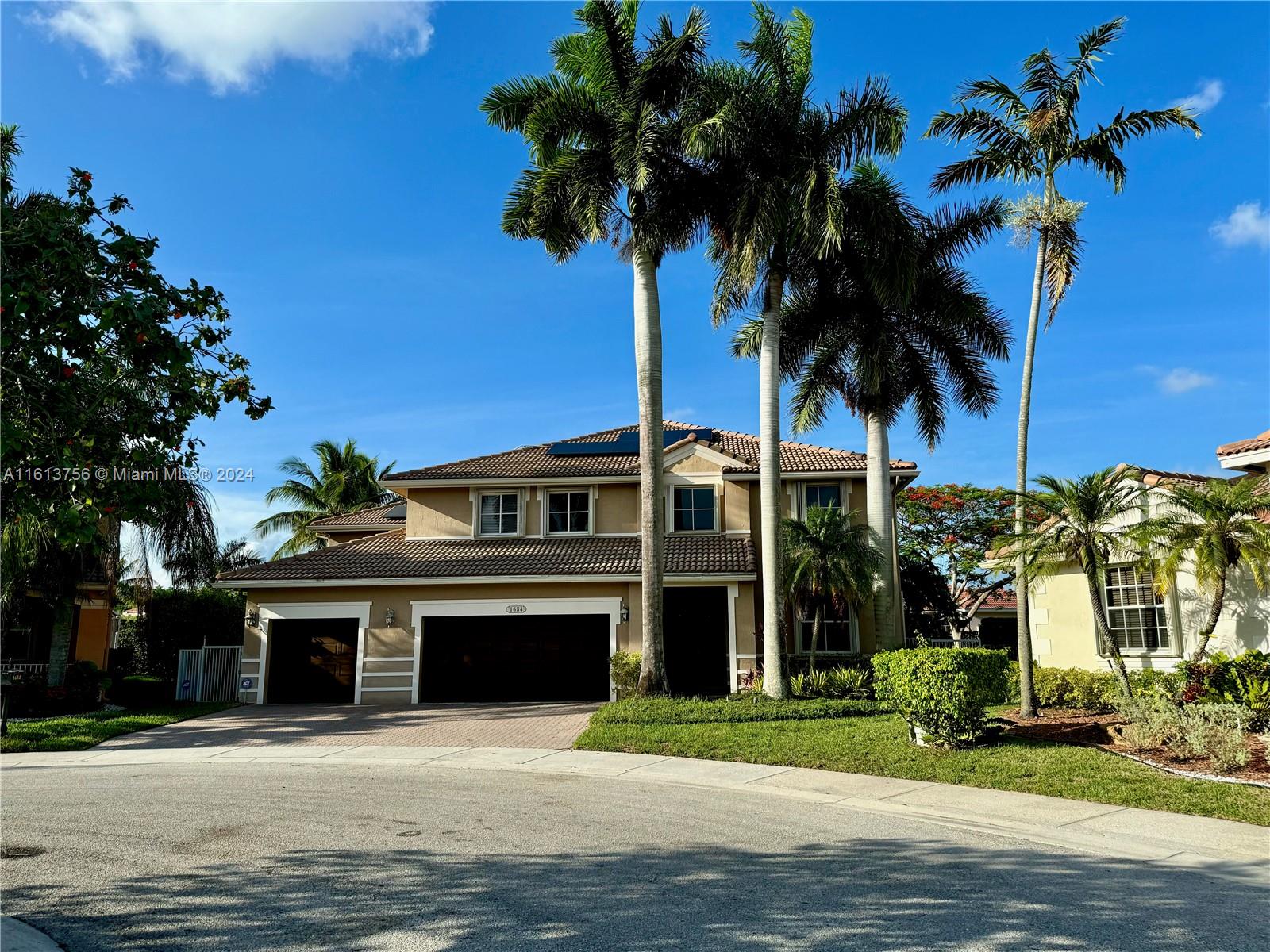 a front view of a house with a garden and palm trees