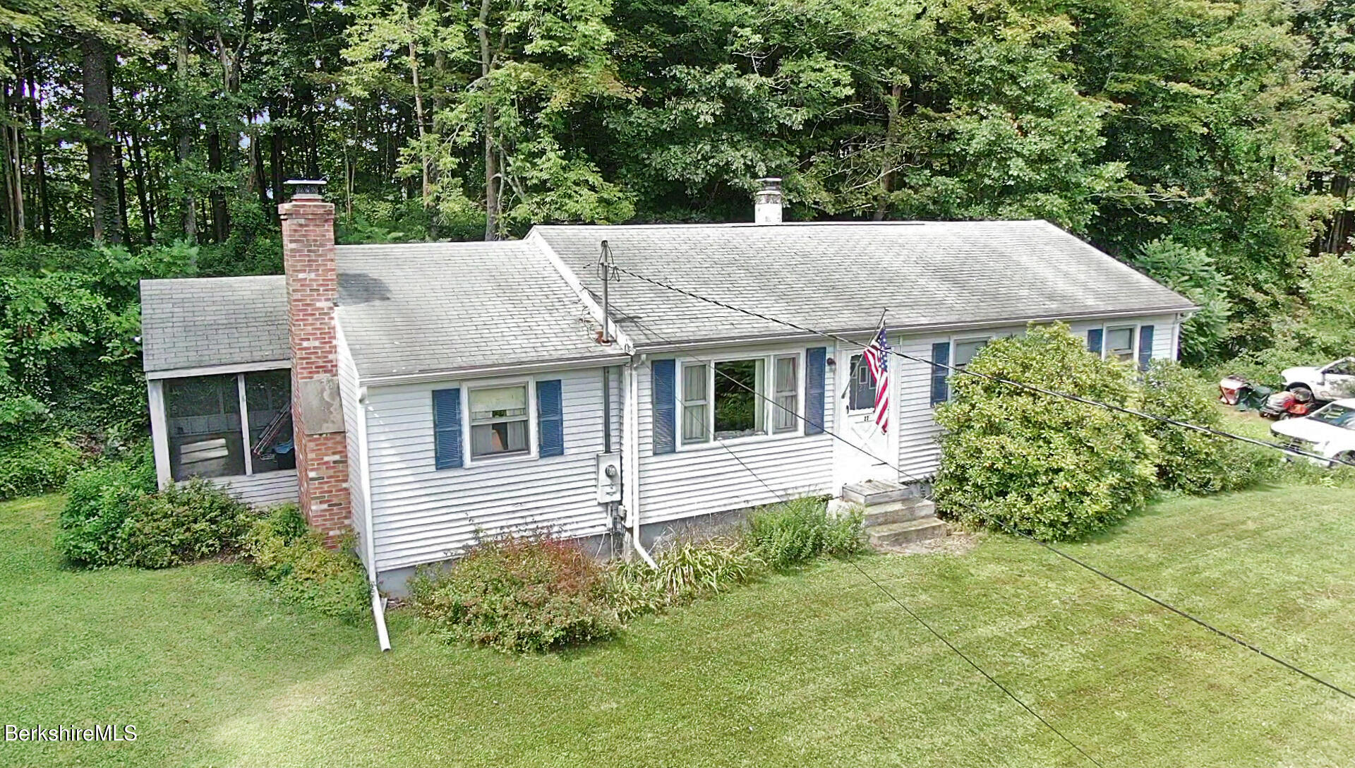 a view of a house with a yard plants and large tree