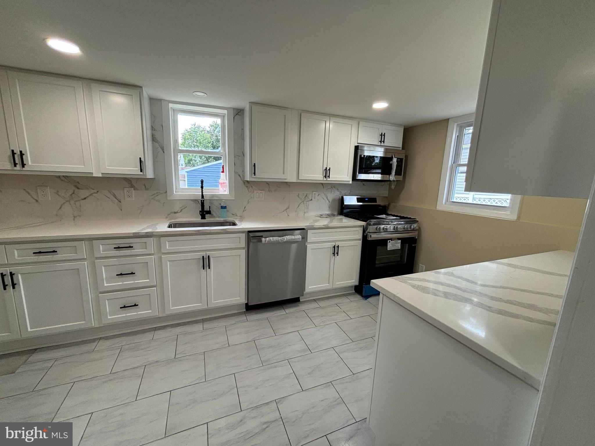 a kitchen with a sink a stove top oven and white cabinets