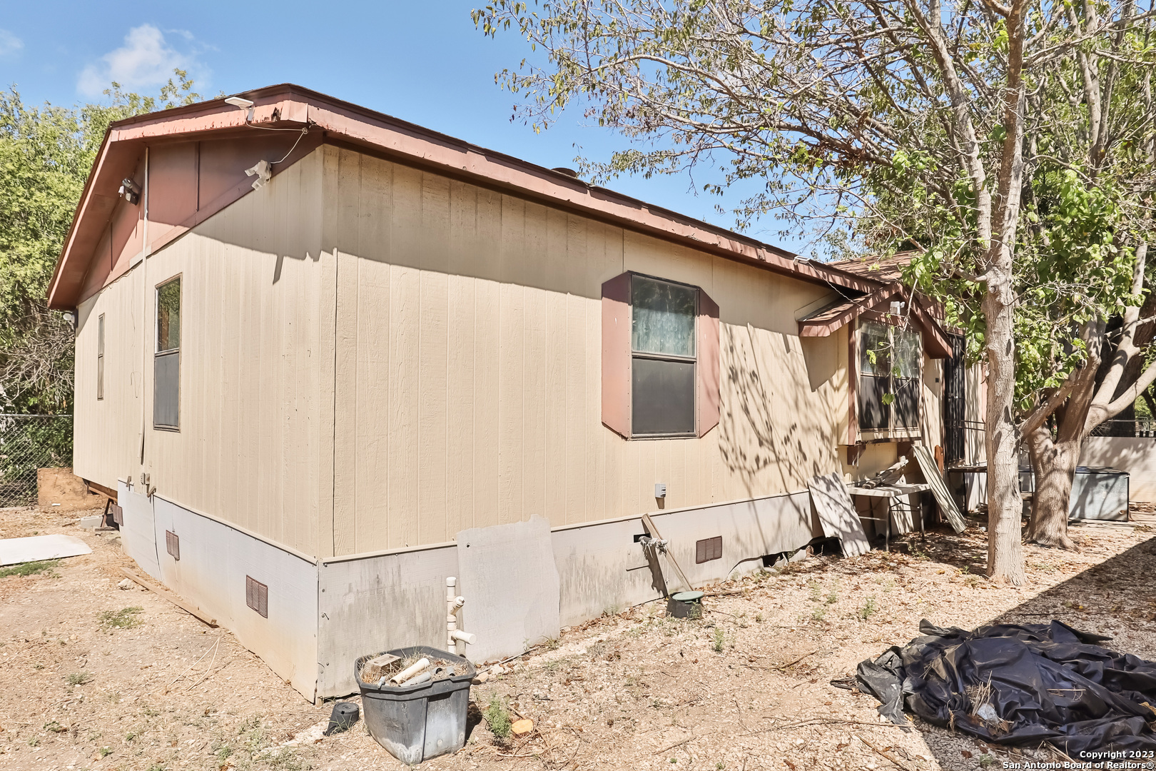 a backyard of a house with large trees and refrigerator