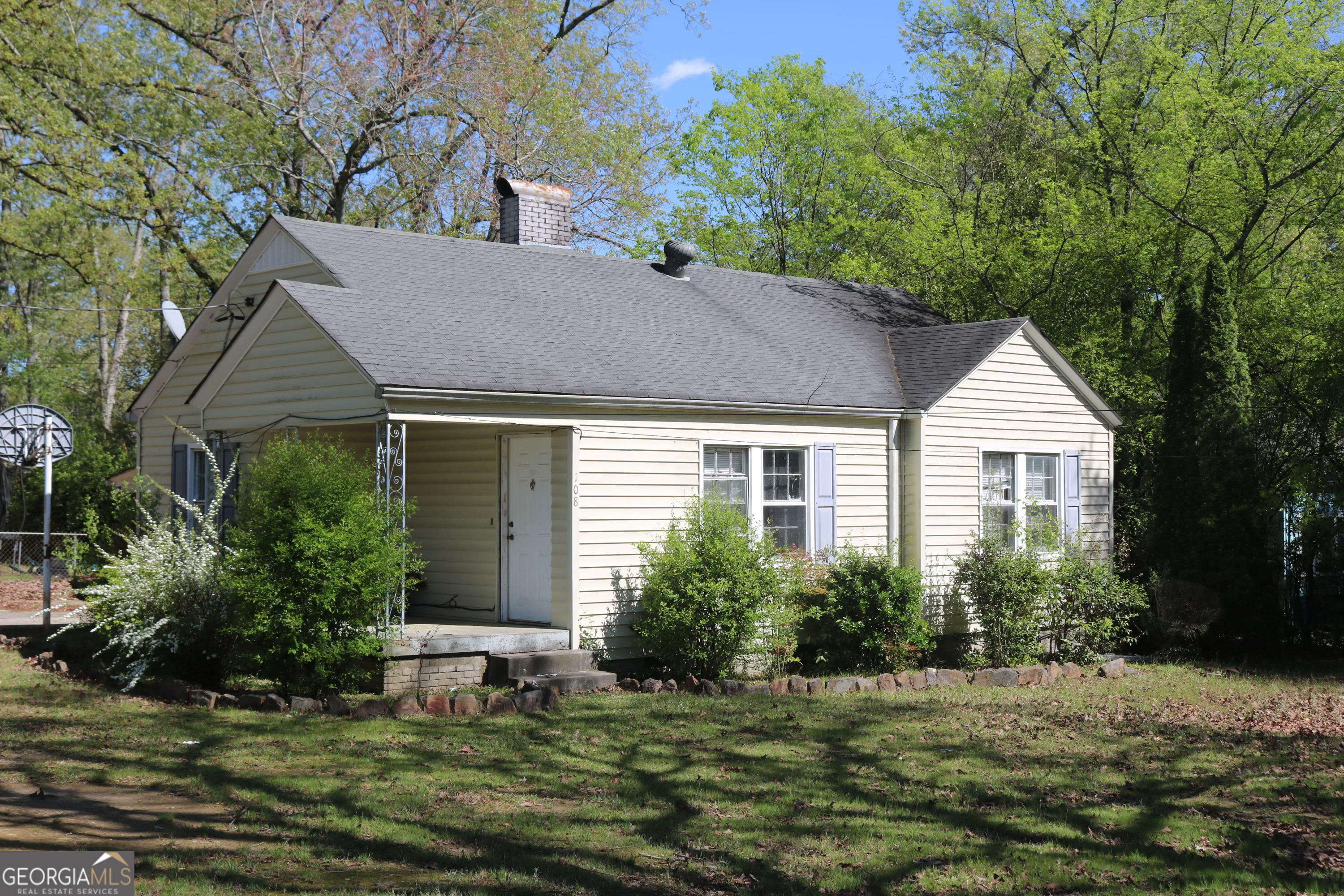 a view of a house with a yard plants and large tree