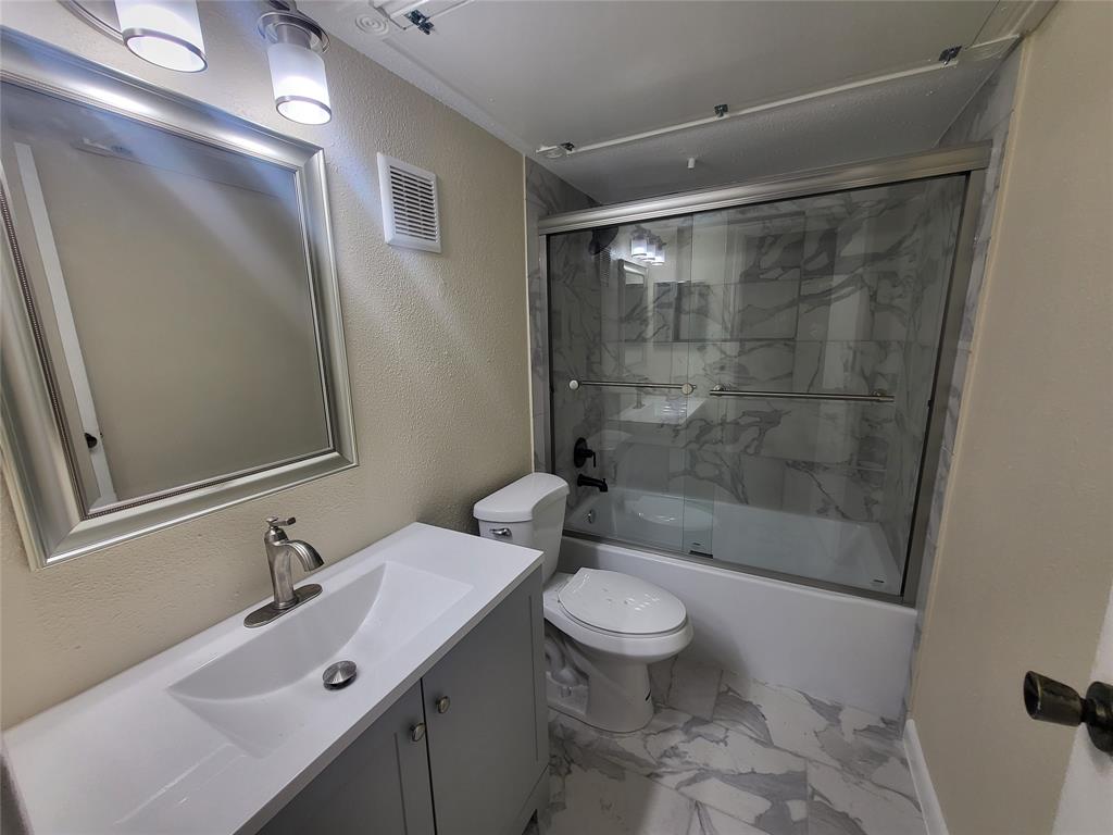 a bathroom with a bathtub shower sink mirror and toilet