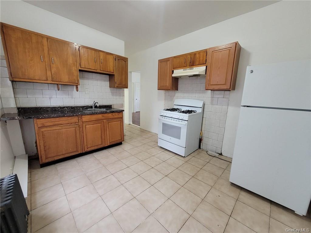 Kitchen with tasteful backsplash, sink, white appliances, and light tile patterned floors