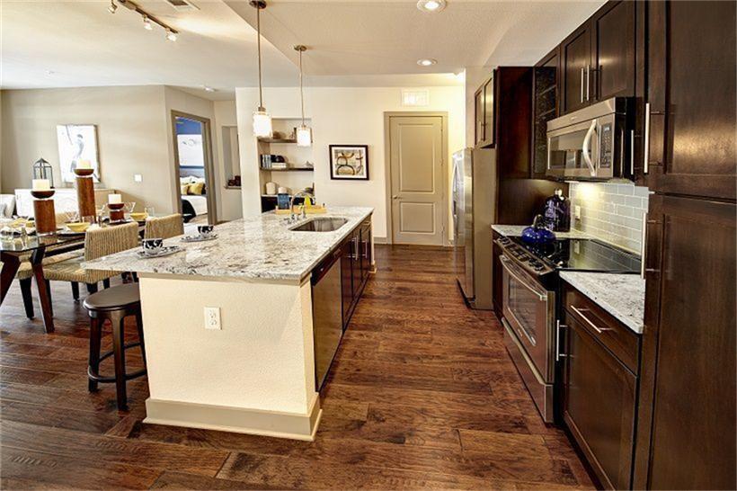 a kitchen with stainless steel appliances kitchen island granite countertop a stove refrigerator and cabinets