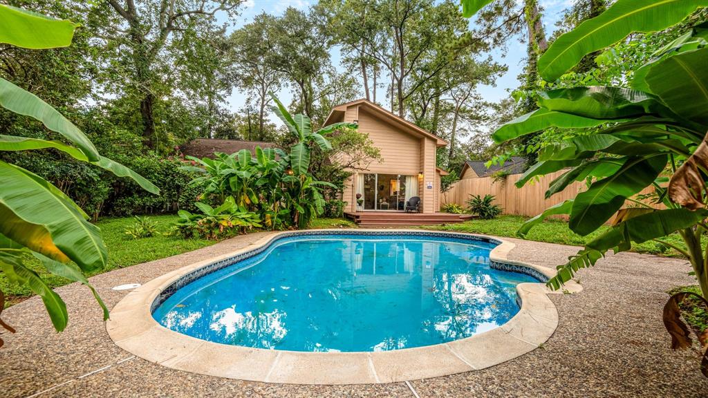 Charming single-family home nestled among mature trees, featuring a private backyard with an inviting in-ground pool and ample patio space, ideal for relaxation and entertaining.