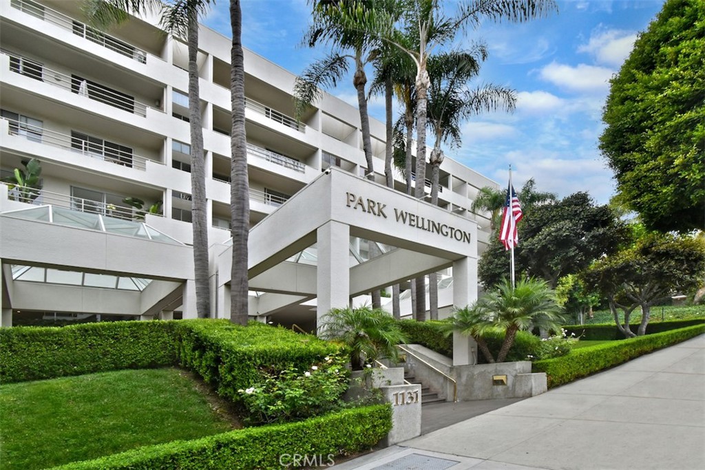 a front view of a multi story residential apartment building with yard and bench