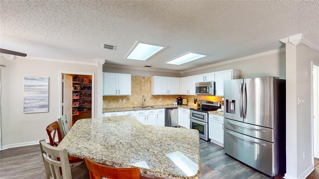 a kitchen with granite countertop a refrigerator stove top oven and sink