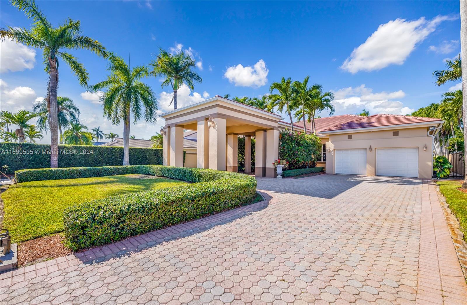 a front view of a house with a garden and palm trees