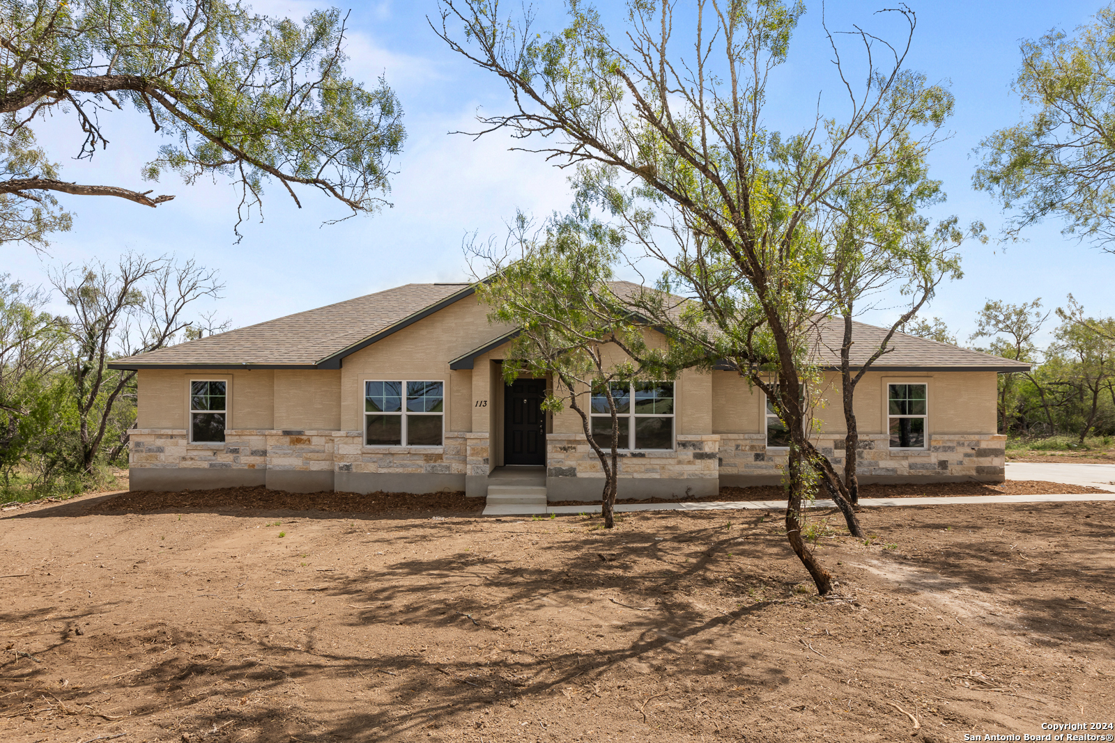 a front view of house with yard and trees around