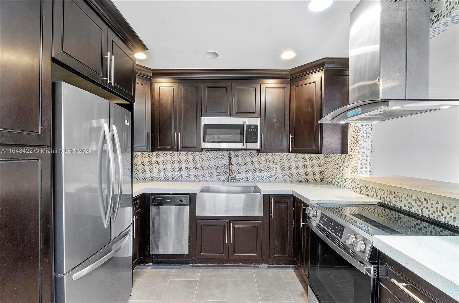 a kitchen with stainless steel appliances granite countertop a sink a stove and a refrigerator