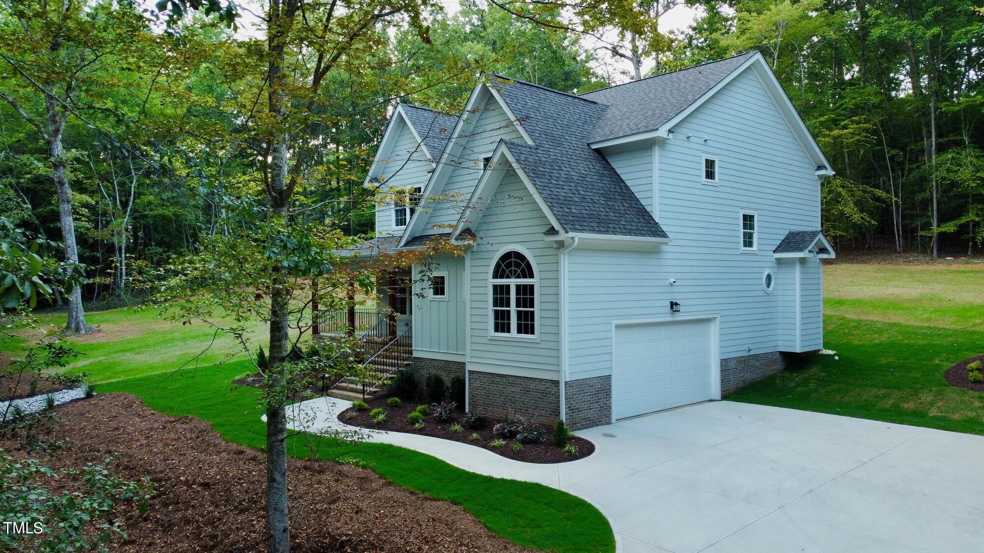 a view of a house with a yard plants and large tree