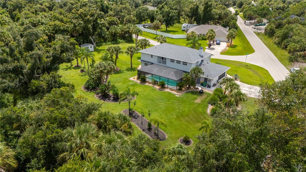 an aerial view of a house with swimming pool and large trees