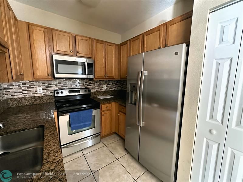 a kitchen with granite countertop a refrigerator stove and microwave