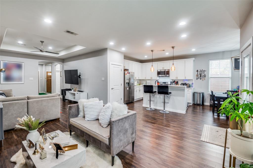 a living room with furniture and kitchen view with wooden floor