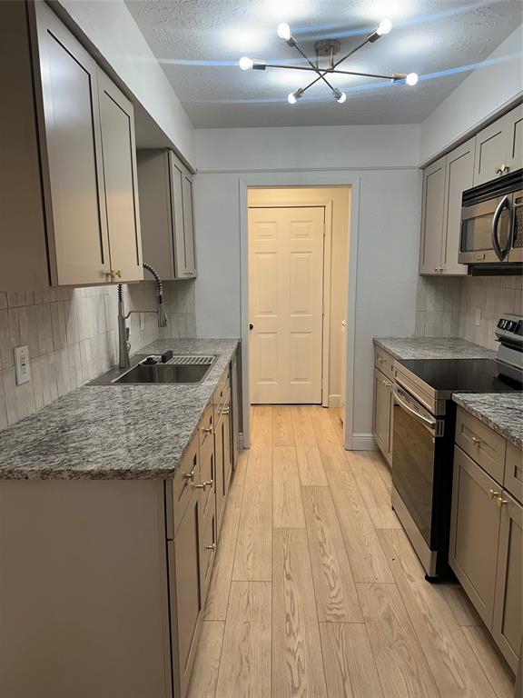 a kitchen with granite countertop a sink stainless steel appliances and cabinets