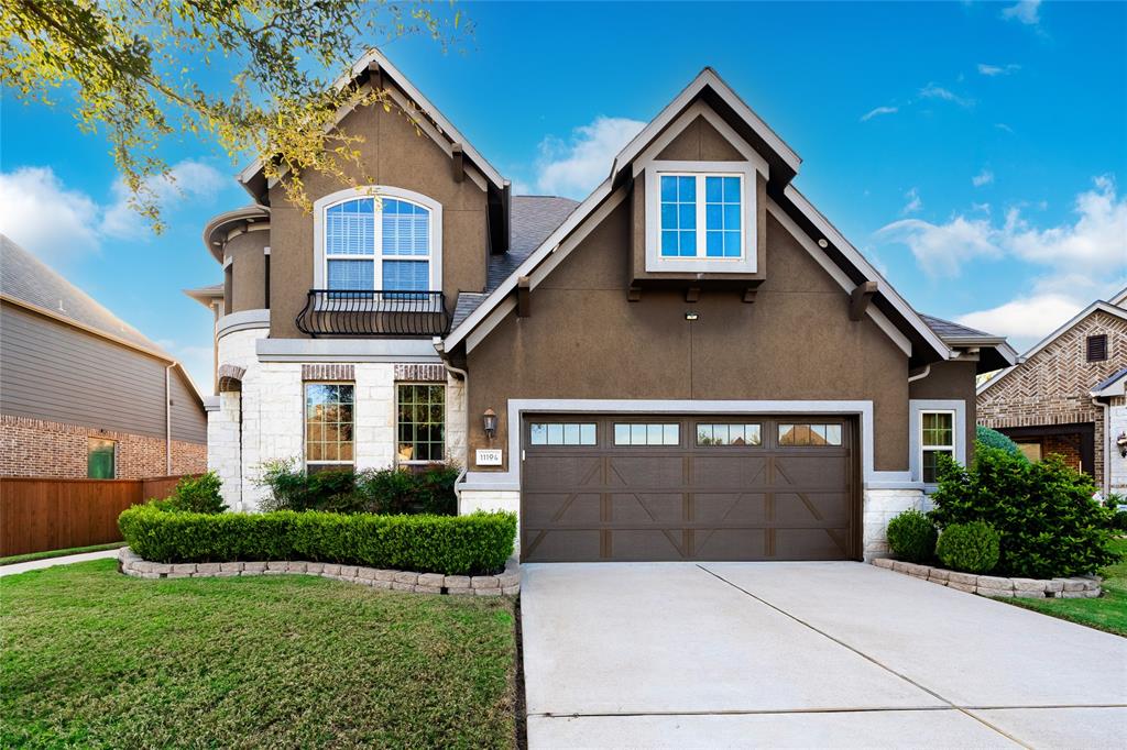 A charming mix of modern and traditional design, perfect for family living. The dark stucco exterior pairs beautifully with white stone accents and a landscaped front yard featuring low-maintenance shrubs. Arched windows and a wrought iron Juliet balcony add elegance, while the pitched roofline enhances character. The home includes a two-car garage with decorative accents and a spacious driveway. Situated in a quiet, well-maintained neighborhood, it blends curb appeal with functional living.