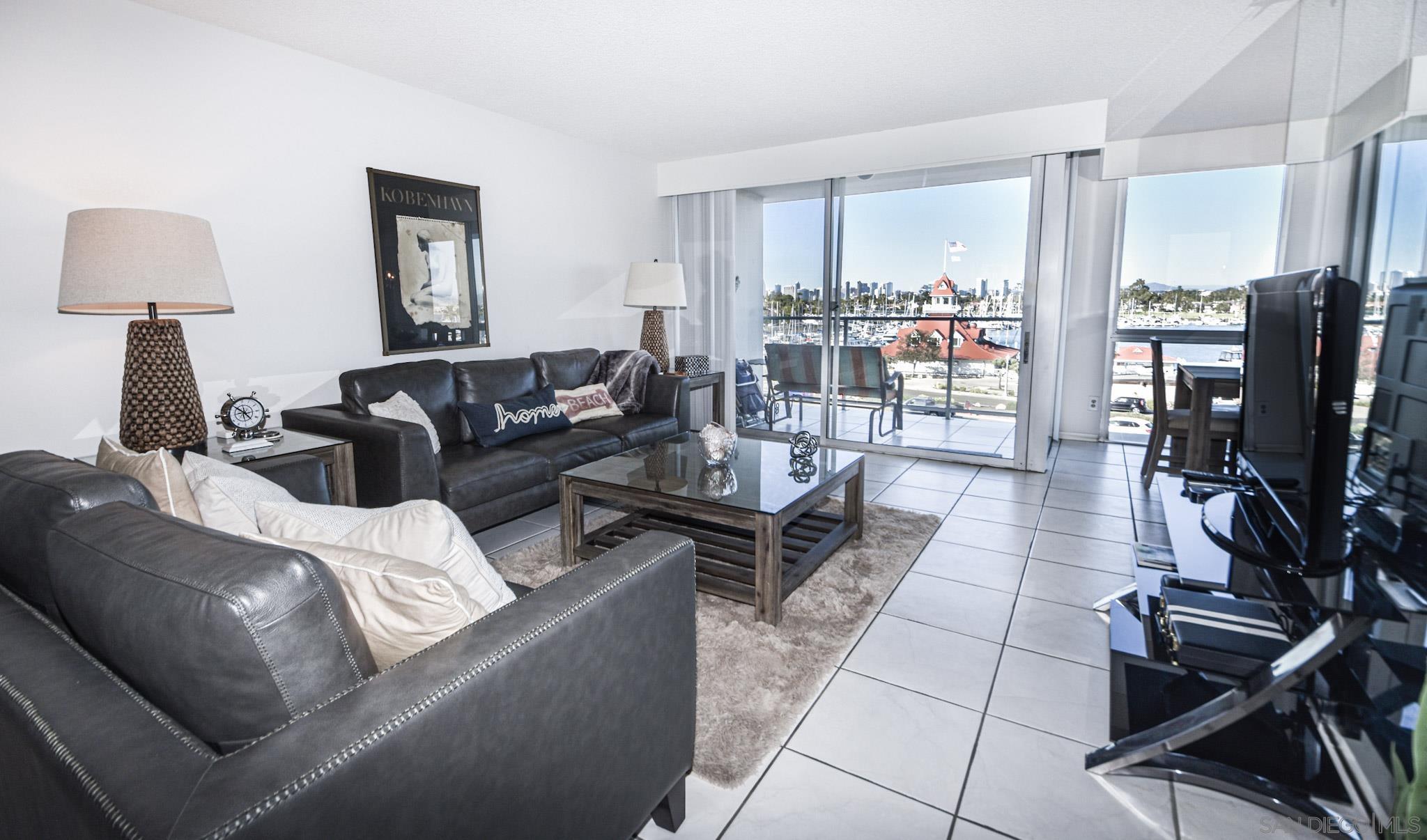 a living room with furniture a flat screen tv and a floor to ceiling window