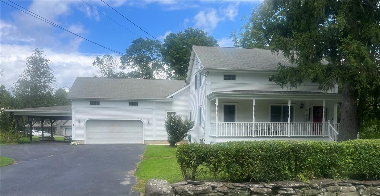 View of front of property with covered porch, a carport, and a garage