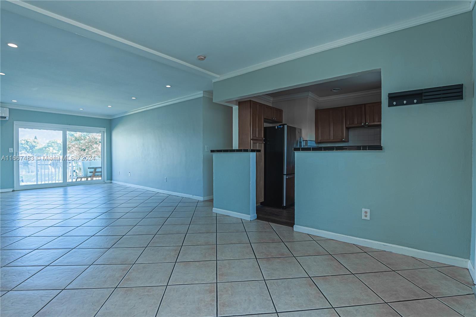 an empty room with windows and refrigerator