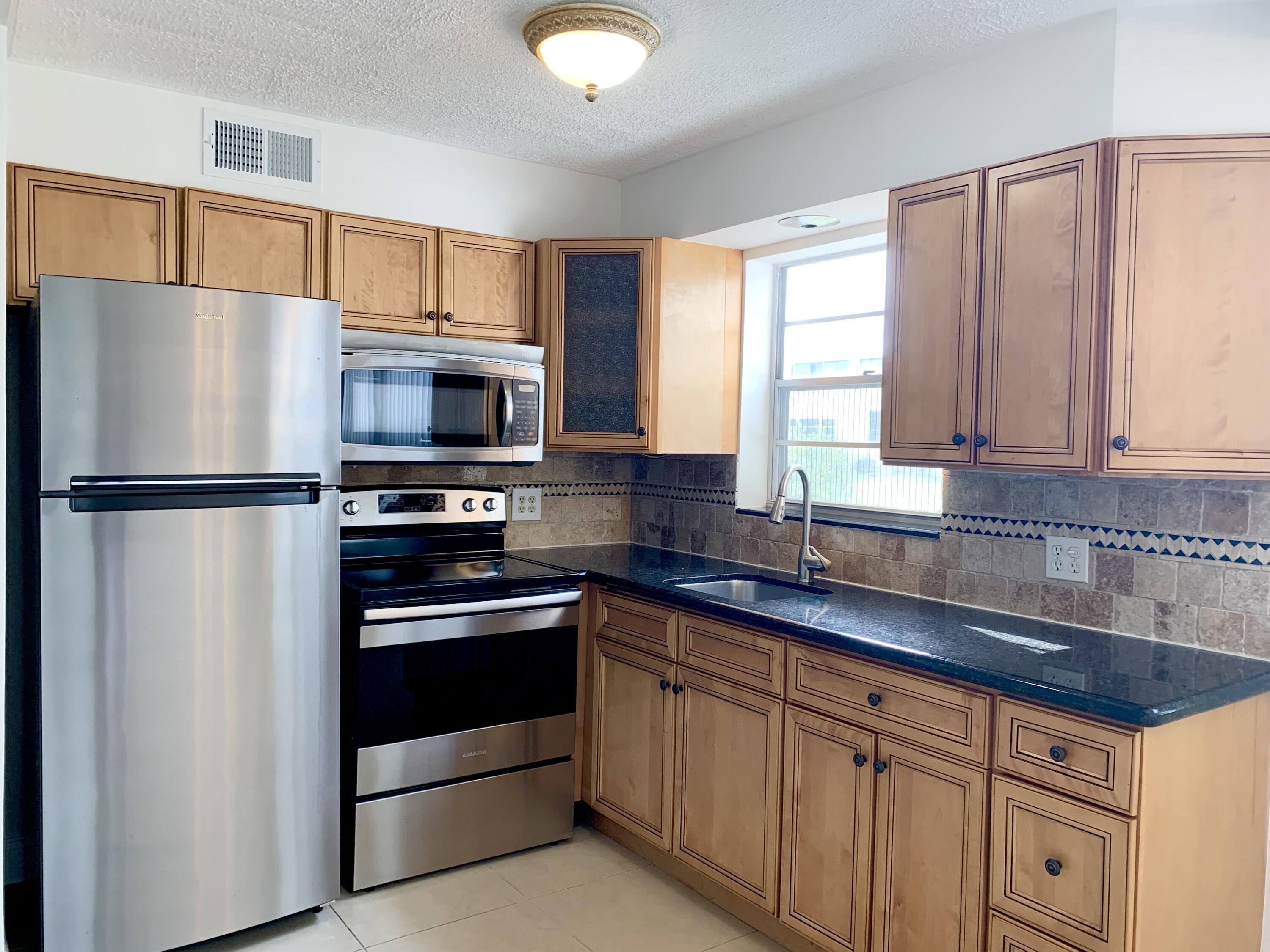 a kitchen with granite countertop a refrigerator stove and microwave