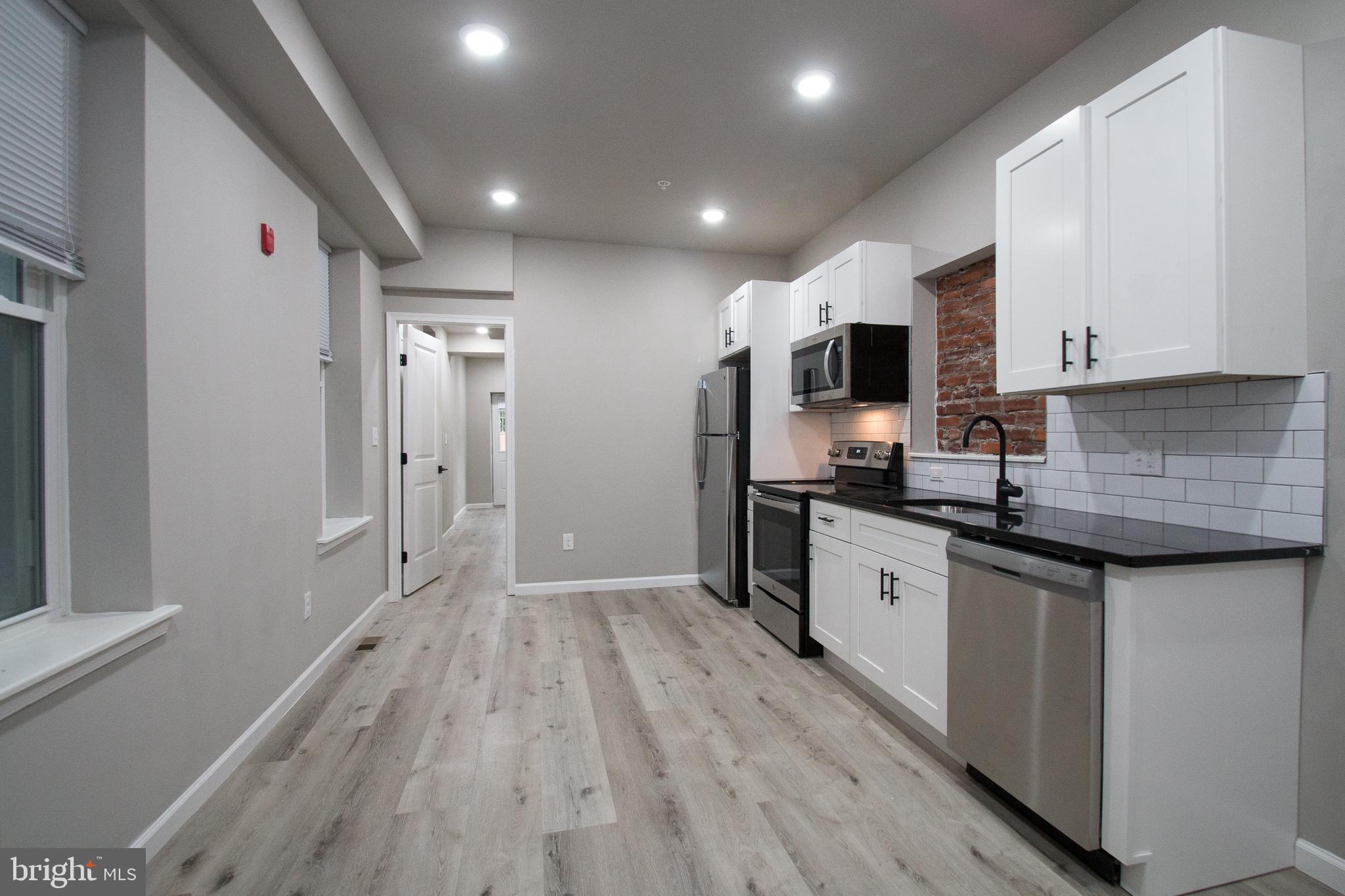 a kitchen with granite countertop a refrigerator stove top oven and sink