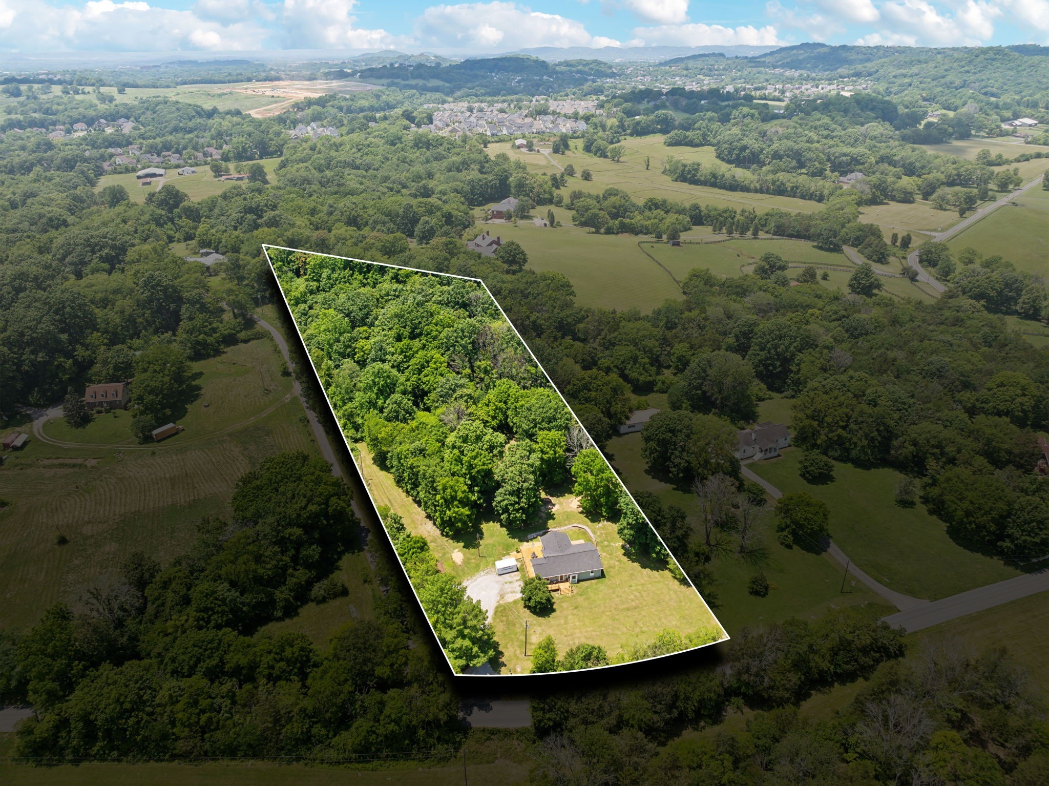 an aerial view of a residential houses with outdoor space and trees