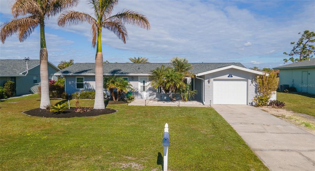 a front view of a house with a yard and palm trees