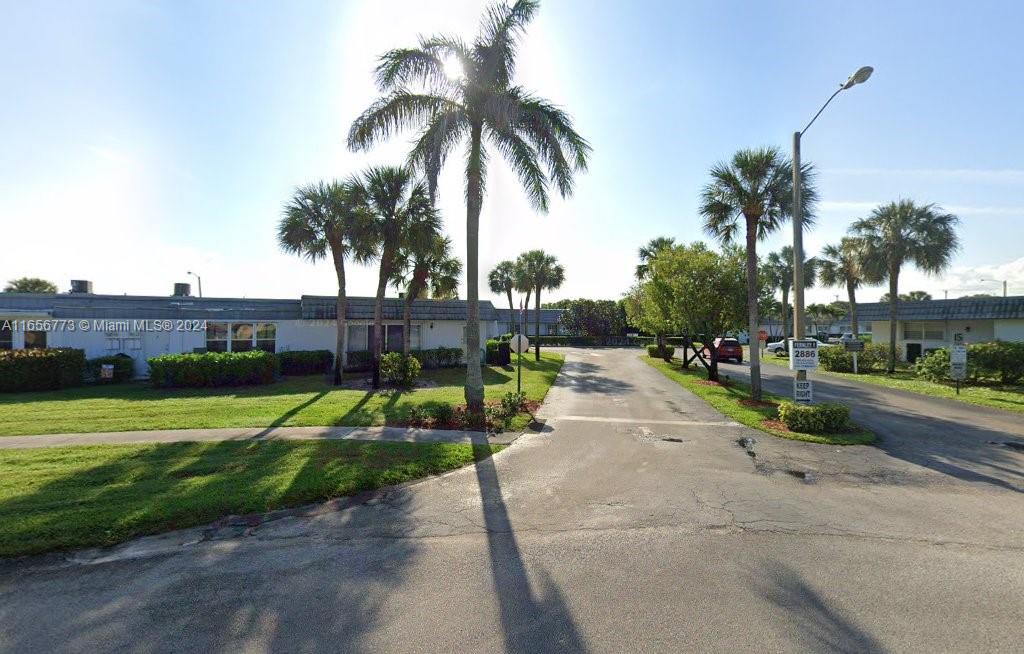 a view of swimming pool with a yard and palm trees