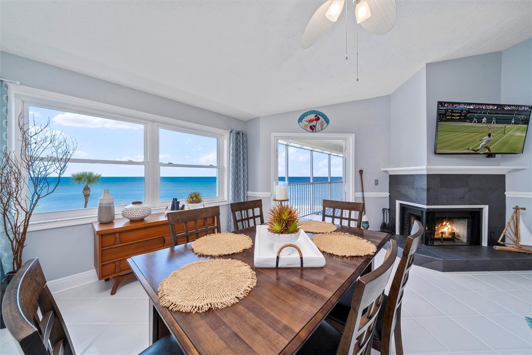 a dining room with furniture a fireplace and large windows