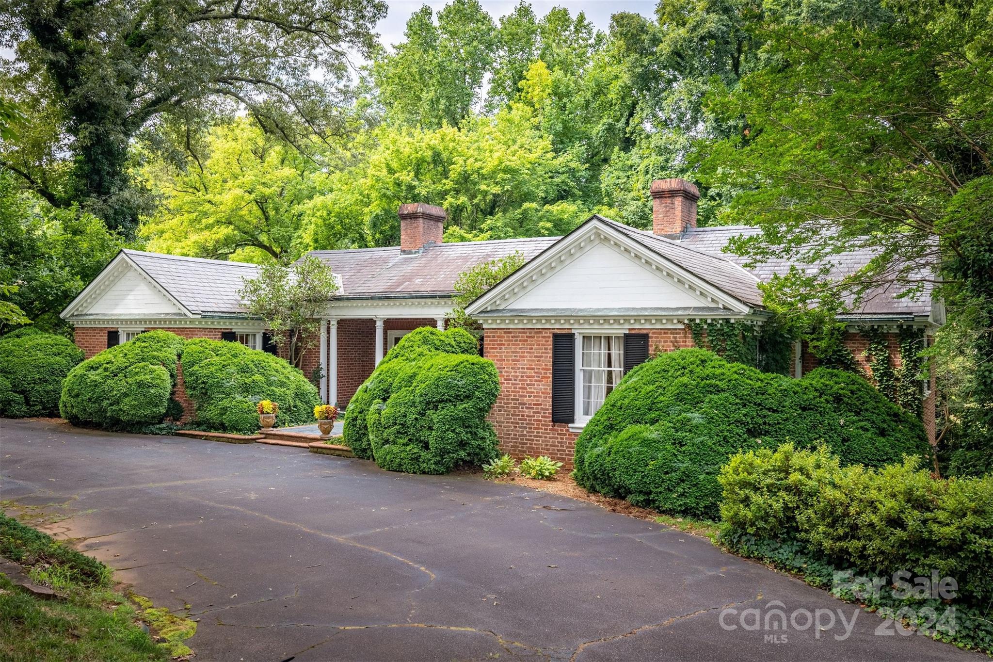 a front view of a house with a garden and trees