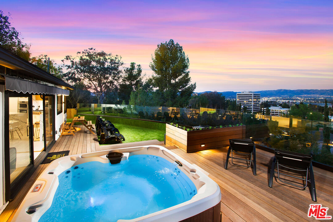 a view of a swimming pool with a lounge chair and tables in the back yard