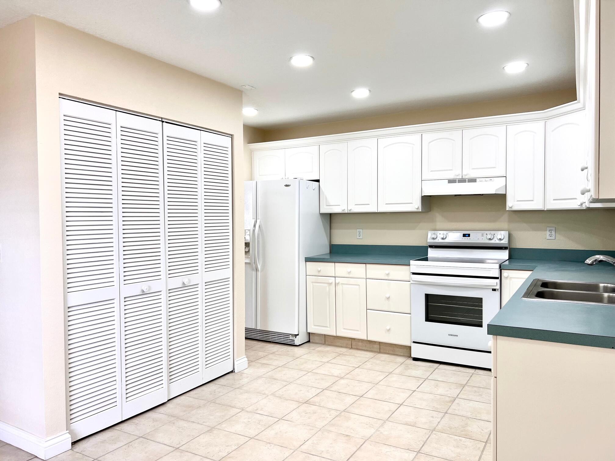 a kitchen with granite countertop a stove a sink and a refrigerator