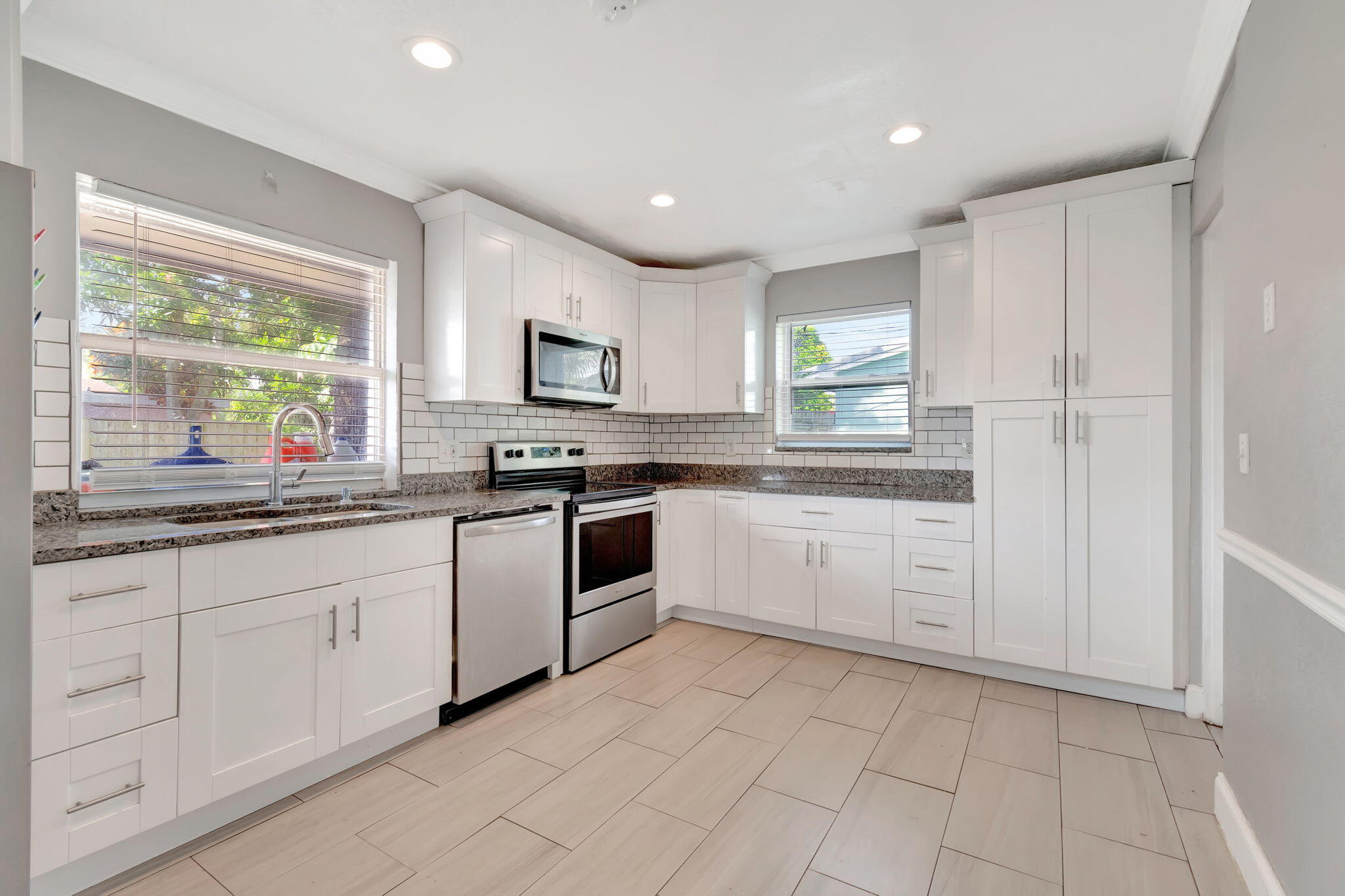 a kitchen with white cabinets appliances a sink and a window