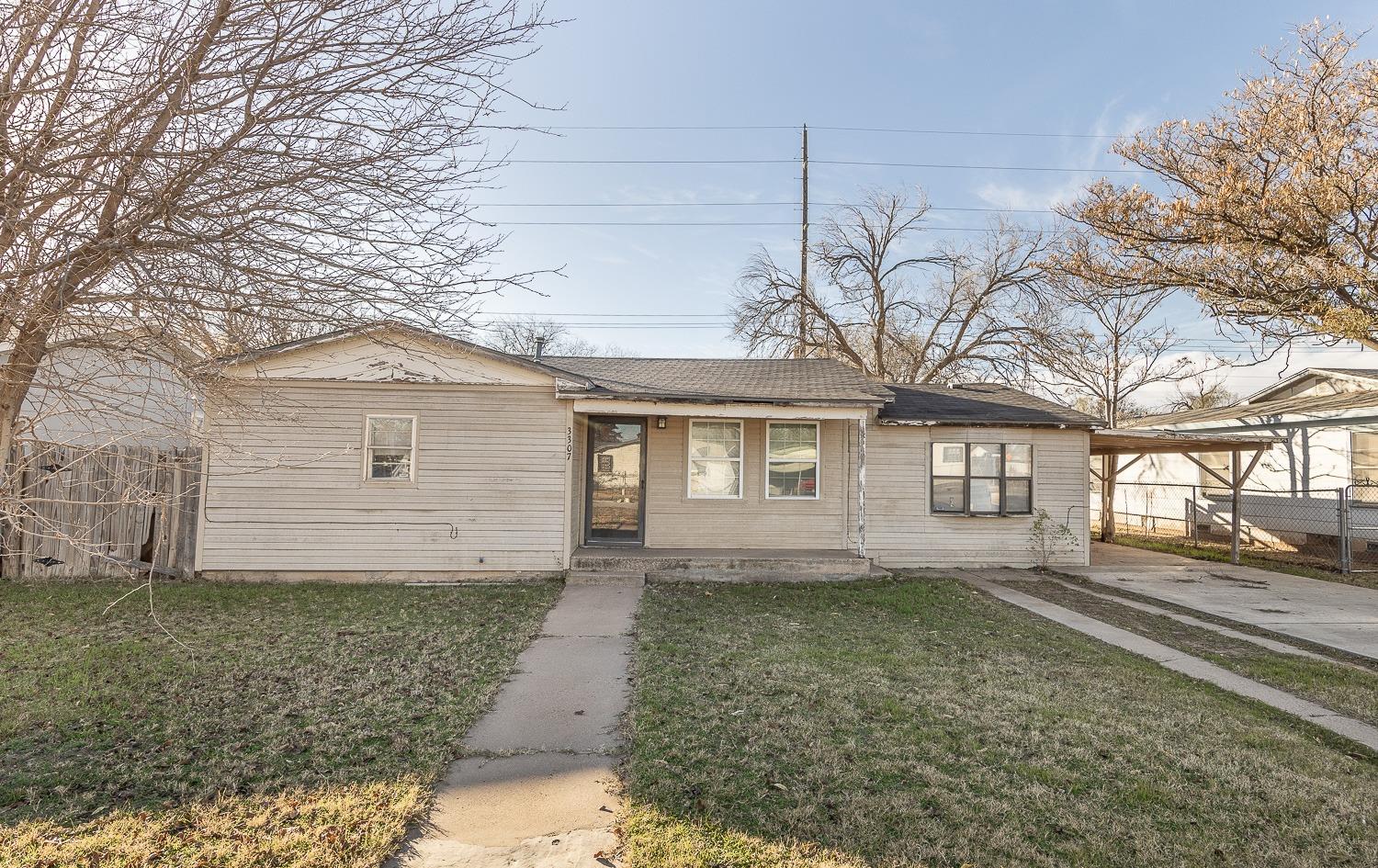 Attached carport on the side of the house with a long cemented driveway