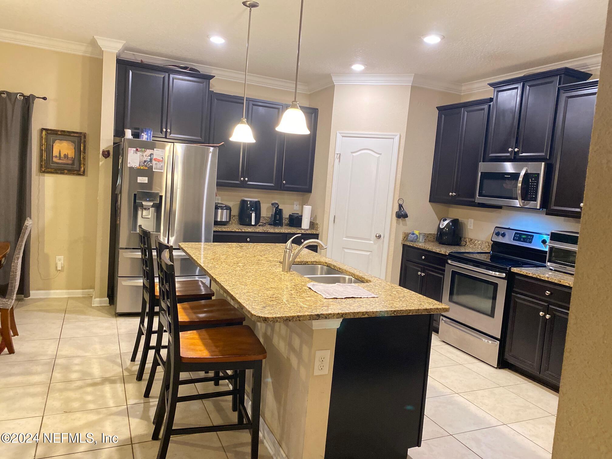 a kitchen with stainless steel appliances kitchen island granite countertop a refrigerator a stove a sink a dining table and chairs with wooden floor