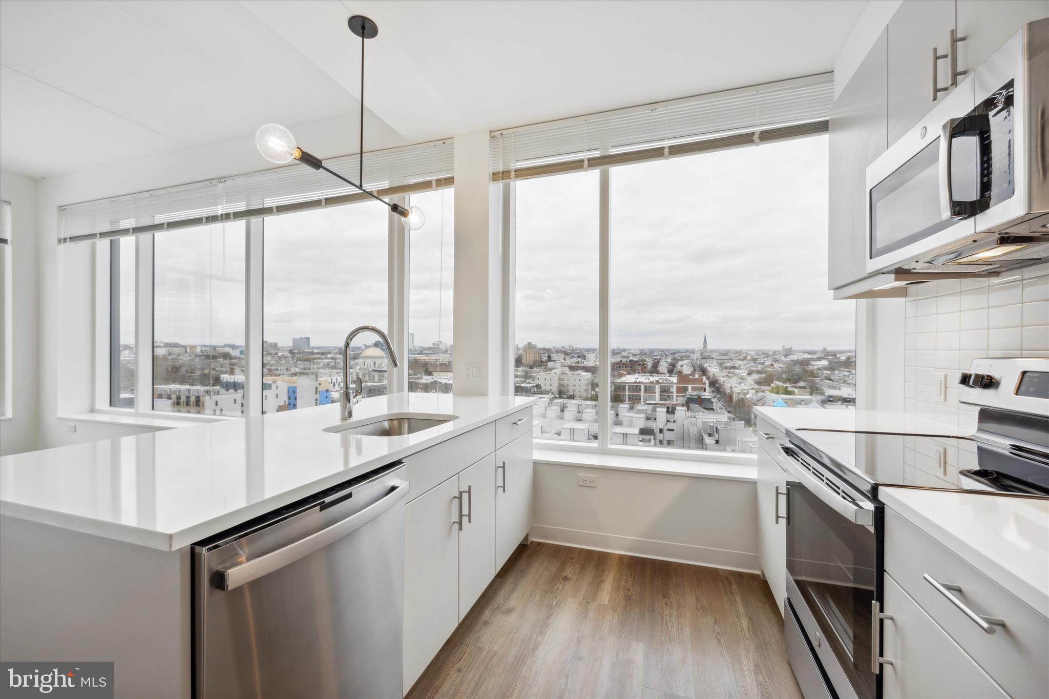 a kitchen with a sink a counter top space stainless steel appliances and a large window